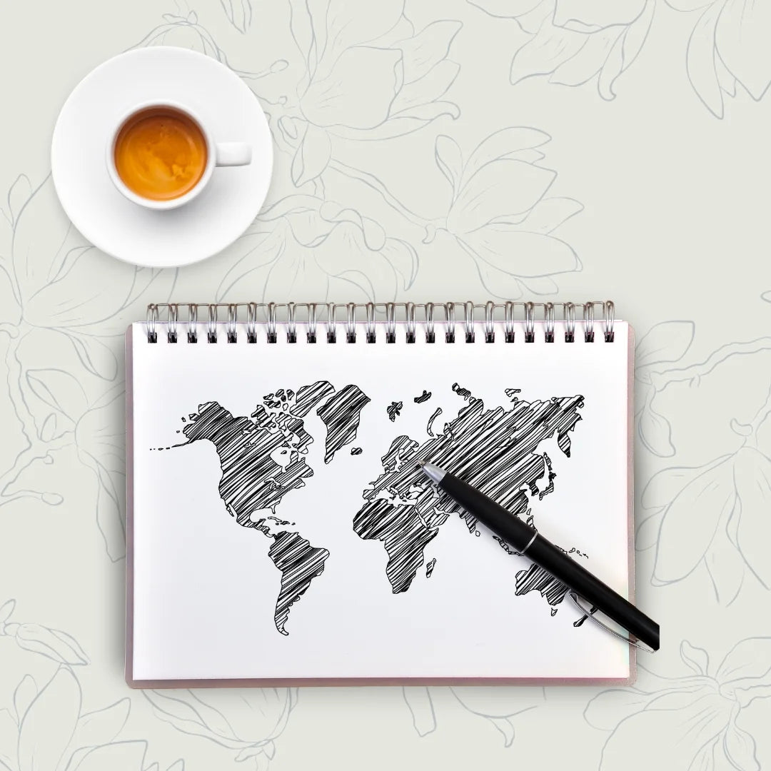 world map drawn on note book next to cup of coffee