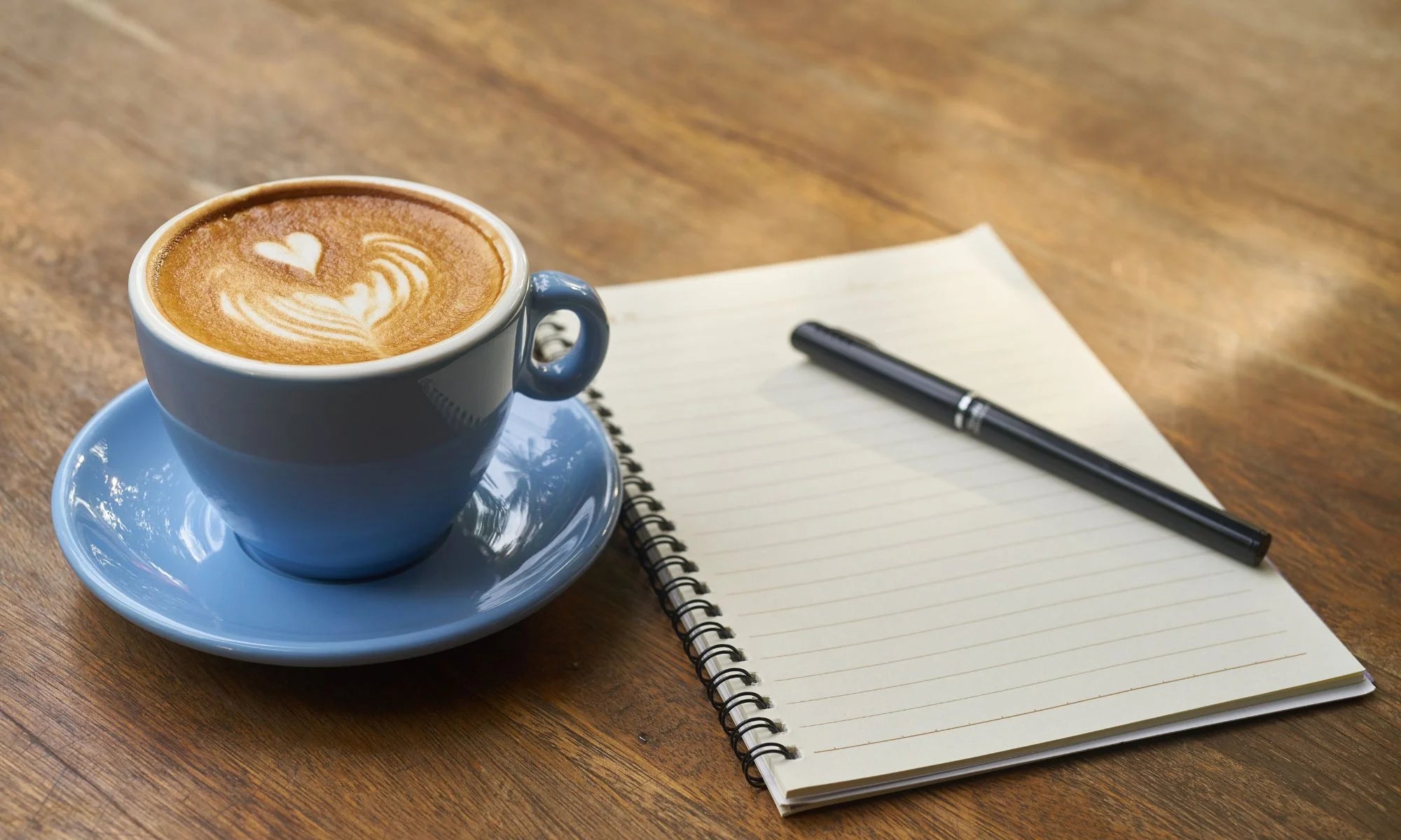 Coffee cup and note book on table