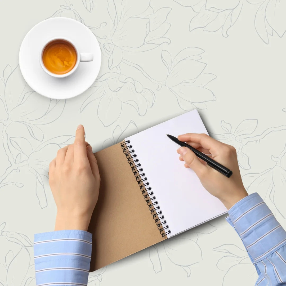 Hands with notebook next to cup of coffee