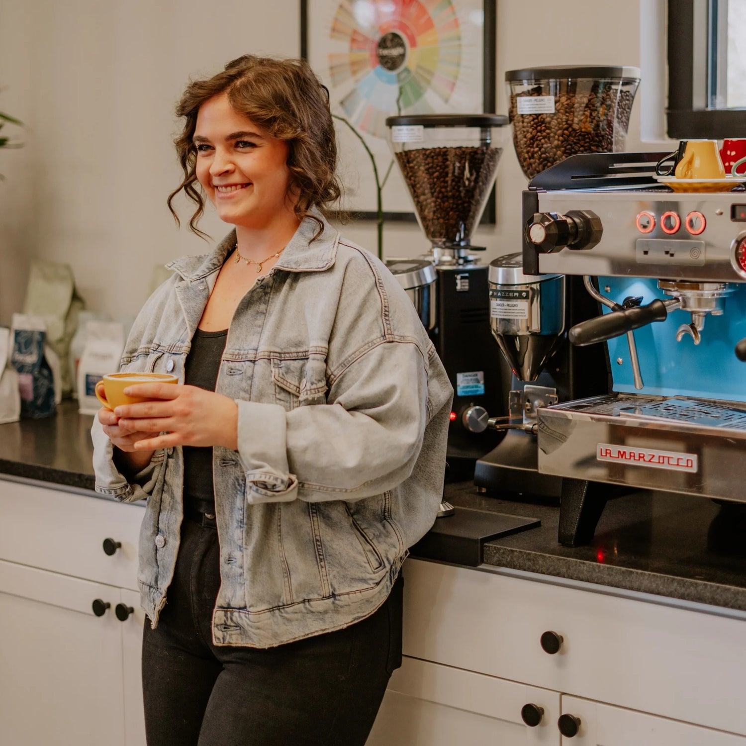 Smiley Woman holds coffee cup with coffee machine behind